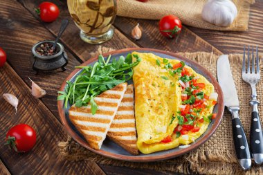 Fried omelette with tomatoes, onion and herbs. Delicious breakfast with eggs and toasts