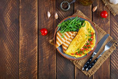 Fried omelette with tomatoes, onion and herbs. Delicious breakfast with eggs and toasts. Top view