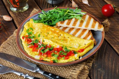 Fried omelette with tomatoes, onion and herbs. Delicious breakfast with eggs and toasts