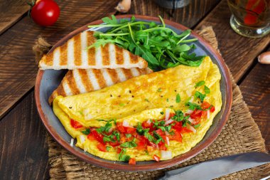 Fried omelette with tomatoes, onion and herbs. Delicious breakfast with eggs and toasts