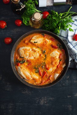 Stew chicken breast with tomato, pepper and spinach in pan. Top view
