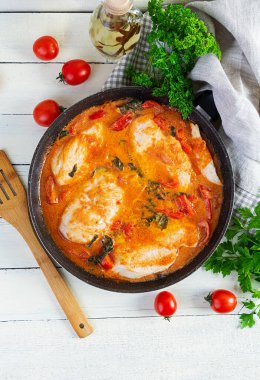 Stew chicken breast with tomato, pepper and spinach in pan. Top view