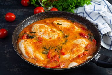 Stew chicken breast with tomato, pepper and spinach in pan
