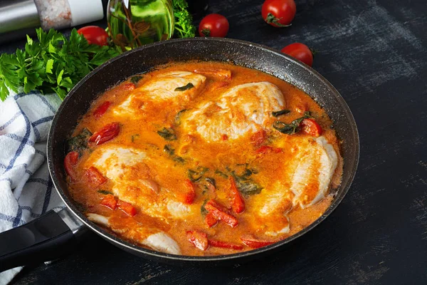 Stew chicken breast with tomato, pepper and spinach in pan