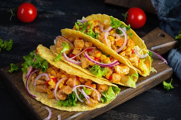 Mexican tacos with corn tortilla. Tortilla with chicken meat, corn, lettuce and onion