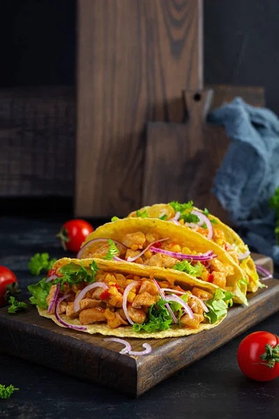 Mexican tacos with corn tortilla. Tortilla with chicken meat, corn, lettuce and onion