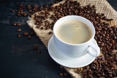 Koyu arkaplanda kahve çekirdeği olan bir fincan kahve. Bir fincan sıcak kahve.
