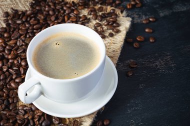 Koyu arkaplanda kahve çekirdeği olan bir fincan kahve. Bir fincan sıcak kahve.