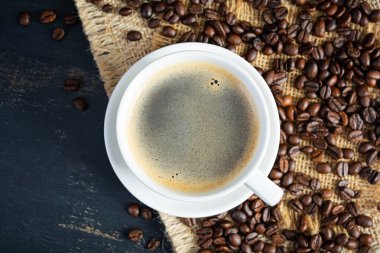 Koyu arkaplanda kahve çekirdeği olan bir fincan kahve. Bir fincan sıcak kahve.