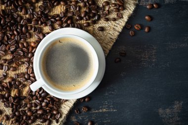 Koyu arkaplanda kahve çekirdeği olan bir fincan kahve. Bir fincan sıcak kahve.