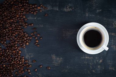 Koyu arkaplanda kahve çekirdeği olan bir fincan kahve. Bir fincan sıcak kahve.