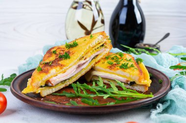 Omlet, jambon, otlar ve peynirli çedar peynirli kızarmış ekmek. Lezzetli ızgara kahvaltı sandviçi