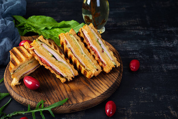 Club sandwich with ham, cheese, tomato and salad. Grilled sandwich with dried tomatoes bread