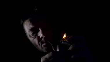 Pipo içen adam. Bir adam sigarasını çakmakla yakar..