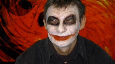 Bloody Halloween theme. An evil joker.Dark creepy joker face against red background.