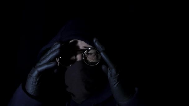 顔にマスクをしたフードと丸メガネのハッカーが犯罪を犯している — ストック動画