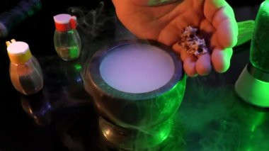 Sihirli havan topu dumanlı ve sihirli kemikli. Büyücünün eli sihirli kemikleri dumanlı bir havana döküyor, sonra da sihirli bir iksir elde etmek için kırıyor..