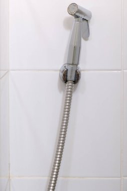 Modern bidet spreyi şehrin tuvaletindeki beyaz fayans duvarında asılı, kullanıcı için temiz ve hijyenik, fotokopi alanı için ön görüş.
