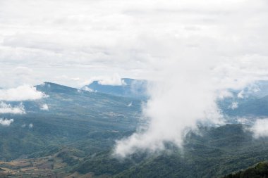 The high mountain range is covered with the mostly cloudy in the early morning of winter, located near the Thai national park., front view with the copy space.