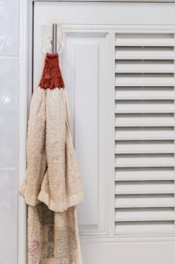 Kumaş el havlusunun yakın çekimi mutfaktaki dolabın beyaz kapısının yanında asılı, arka plan manzaralı..