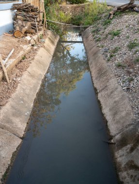 Beton drenaj hendeği, köyün kırsal kesimindeki bir çiftçinin evinin önünden geçiyor..