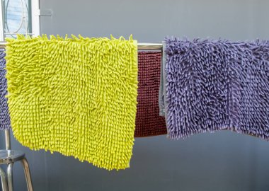 Temizlikçi ayak kazıyıcısı, duvarın yanında yıkadıktan sonra metal çizgide asılı duruyor, fotokopi alanının önünde..