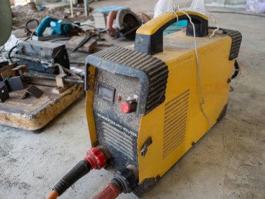 Ev geliştirme projesinde kullanılmak üzere beton zeminde bulunan eski çevirici kaynak makinesi, kopya alanı ile ön görünüm.