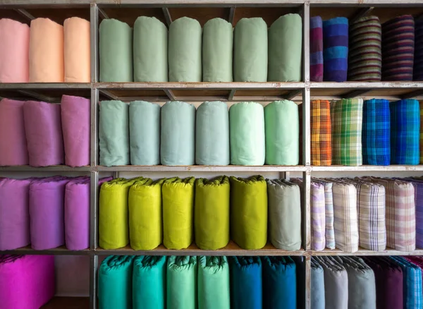 The handmade woven silk rolls in traditional Thai style are on shelves inside a local clothing store in Thailand, front view with the copy space.
