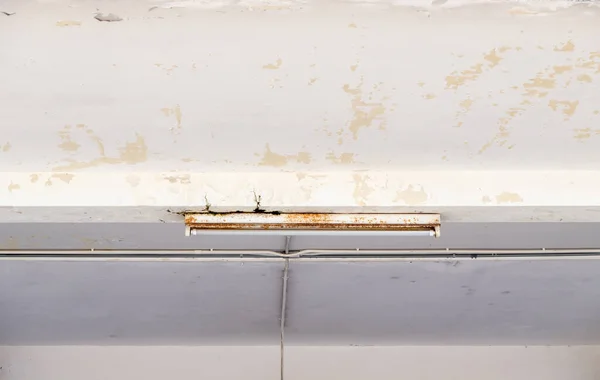 The fluorescent tube on the concrete ceiling of the large warehouse, front view with the copy space.