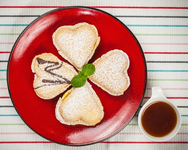Ванильное сердце на красной тарелке и кофе — стоковое фото