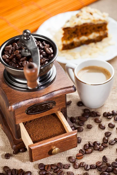 Coffee grinder, cup of coffee and cake — Stock Photo, Image