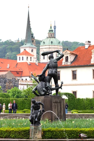 Prague, Tsjechië - 8 mei 2013: een van de bronzen beelden in wallenstein tuinen (valdstejnska zahrada). op de achtergrond is het paleis wallenstein eerste barokke paleis in Praag. — Stockfoto