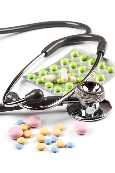 Multi color pills spills around the stethoscope, one blister with green pills, isolated on white — Stock Photo, Image