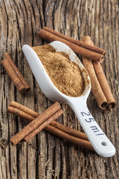 Ground cinnamon spice ,and five pieces of cinnamon barks, old wood background