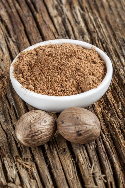 Spice nutmeg in whole and ground in a white bowl — Stock Photo, Image