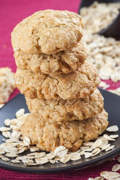 Five oatmeal cookies on red background, scattered oat flakes — Stock Photo, Image