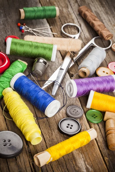 Verspreide naaien spoelen en knoppen, schaar en naalden — Stockfoto