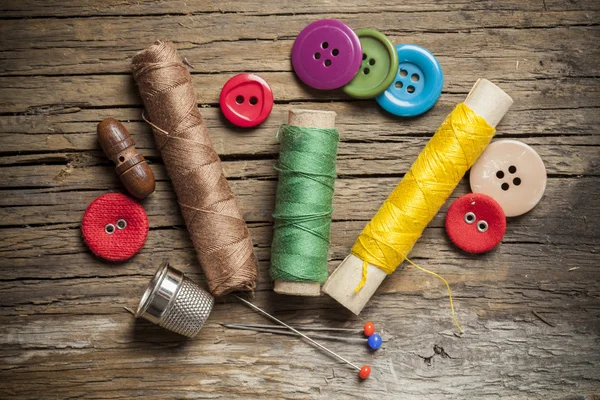 Conjunto de botones de costura de colores e hilos de bobina sobre fondo de madera — Foto de Stock