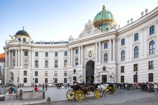 Vienna, Oostenrijk - augustus 30, 2013: hoofdingang aan hofburg paleis paarden getrokken karren wachten op toeristen bij de hoofdpoort naar hofburg paleis — Stockfoto