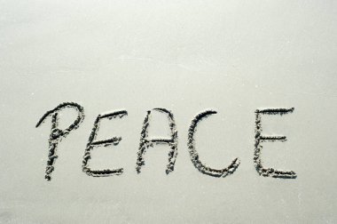 Concept or conceptual Peace text handwritten in sand on a beach  in an exotic island for peacefullness, summer, sea, ocean, calendar, travel, holiday, sunny, tourism, resort, time and relaxation