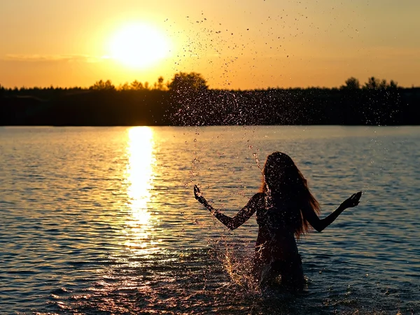 Meisje permanent in het meer bij zonsondergang — Stockfoto