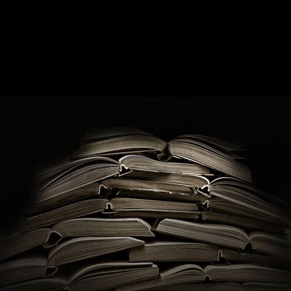 黒い背景の古い本の山 — ストック写真