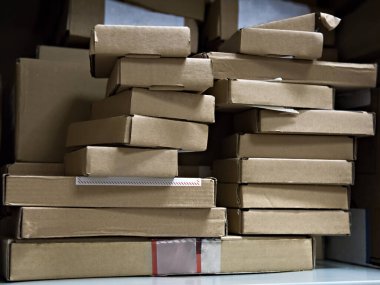 Servis merkezinin rafında bilgisayar parçaları olan karton kutular.