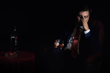 Sandalyedeki iş adamı umutsuzluğa kapılır ve alkol içer. 