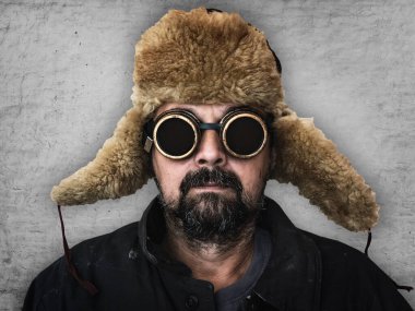 Kulaklık takmış, fötr şapkalı ve ceketli bir adam. 