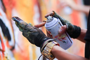Graffiti sanatçısı bir duvarı sprey boyayla boyuyor, grafiti sprey boyayla boyama sanatlarından biri..