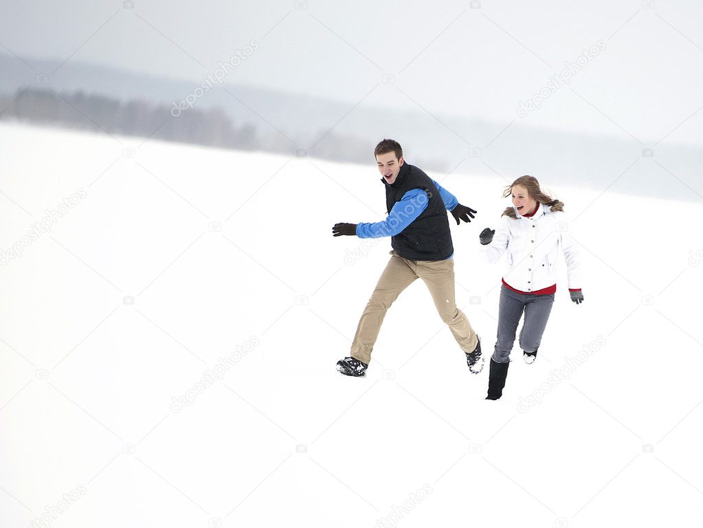 Young happy couple running through a snowy field