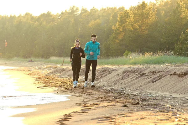Молодой человек и женщина бегут вдоль набережной — стоковое фото
