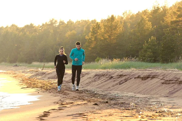 Young man and woman running along the waterfront — Stock Photo, Image