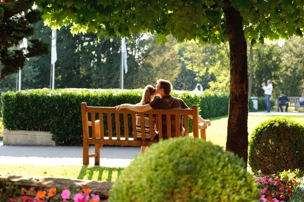 Parktaki bankta oturan genç çift Stok Resim